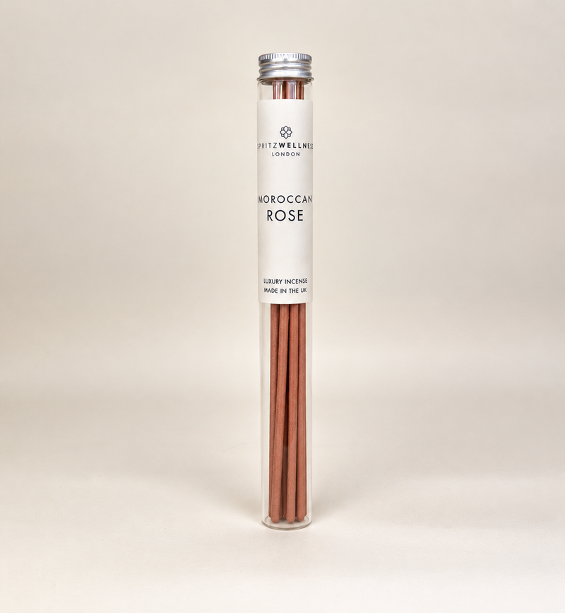 A glass tube of Spritz Wellness Moroccan Rose incense sticks on a soft beige background
