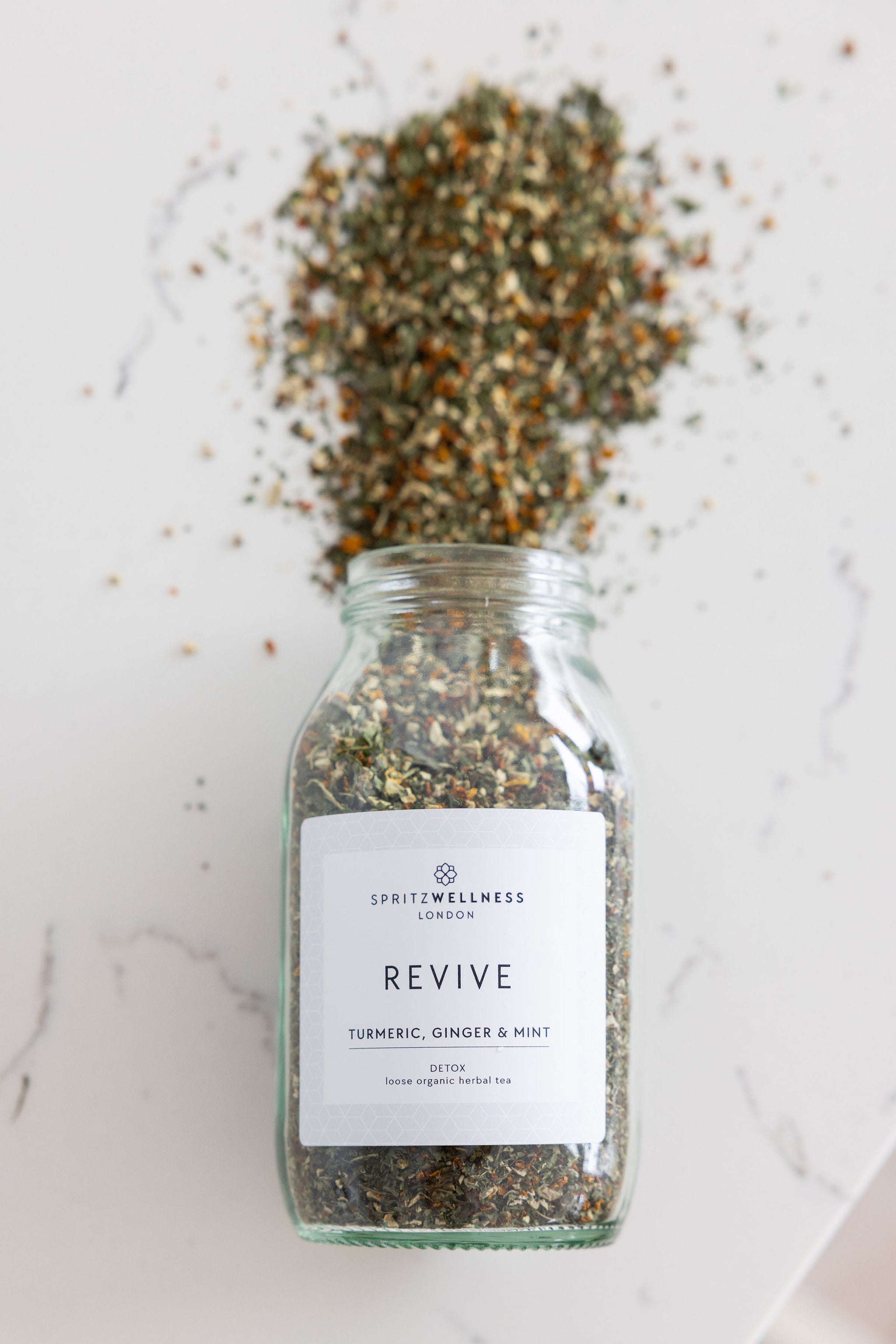 Jar of 'Revive' spice blend with a label on a marble surface by Spritz Wellness