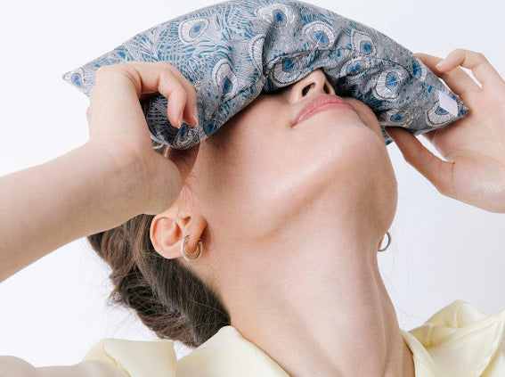 spritz wellness here blue eye pillow draped over woman's eyes 