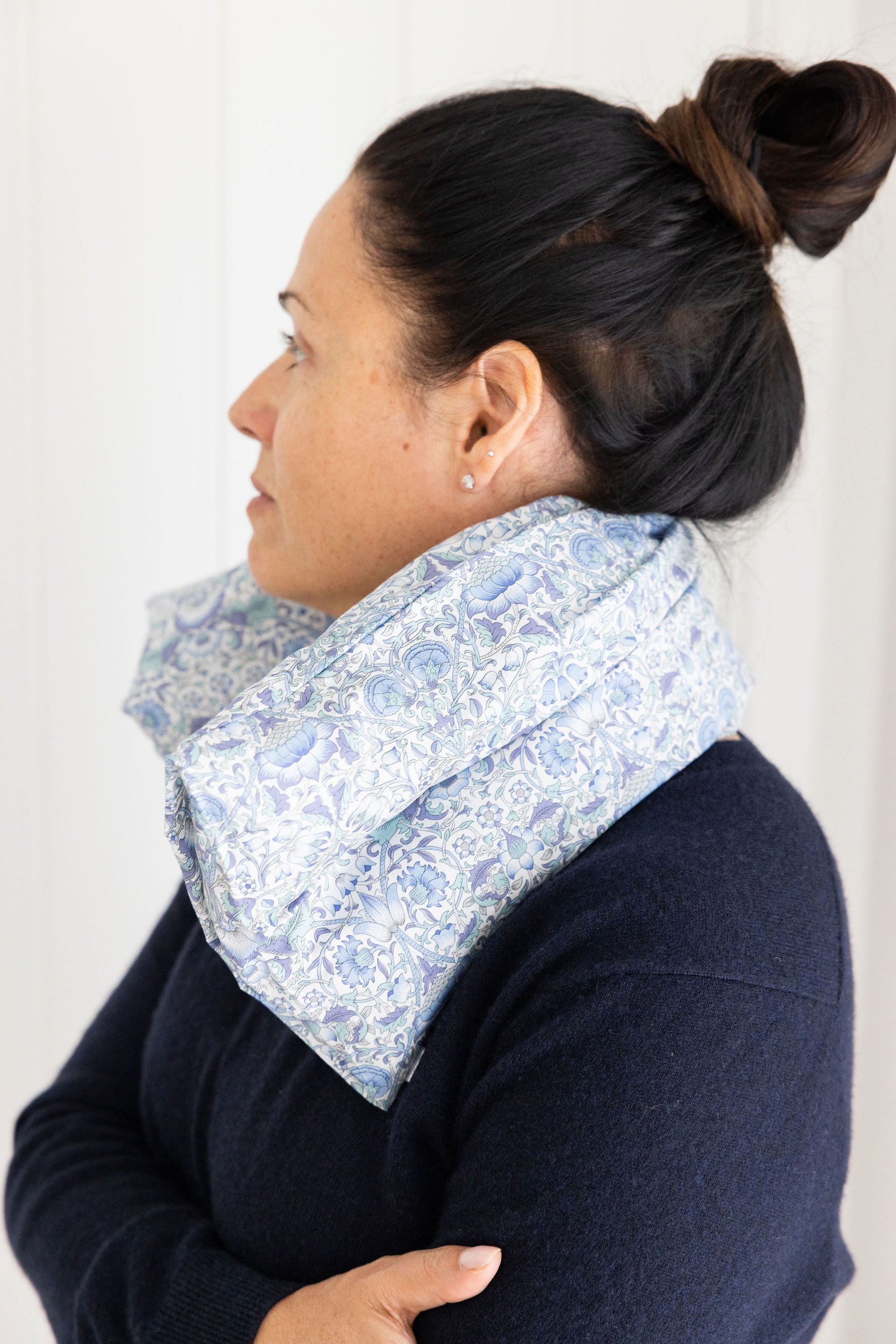 Woman wearing a blue floral scarf around her neck against a white background from Spritz Wellness