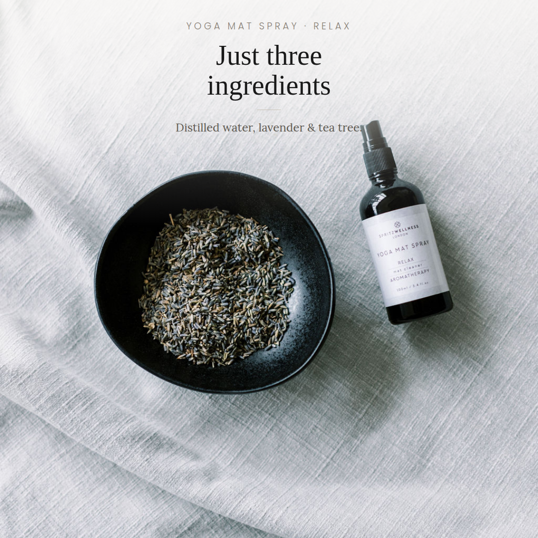 A yoga mat spray bottle next to a black bowl filled with dried lavender and tea tree leaves, set on a light gray textured fabric background with text overlay reading 'Just three ingredients'.