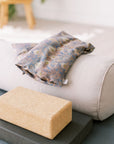 Lavender Wheat Bag, Liberty fabric, use heated or chilled, removable washable cover, with patterned cover and Spritz Wellness label on a yoga mat.