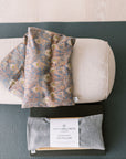 Lavender Wheat Bag, Liberty fabric, use heated or chilled, removable washable cover, with patterned cover and Spritz Wellness label on a yoga mat.