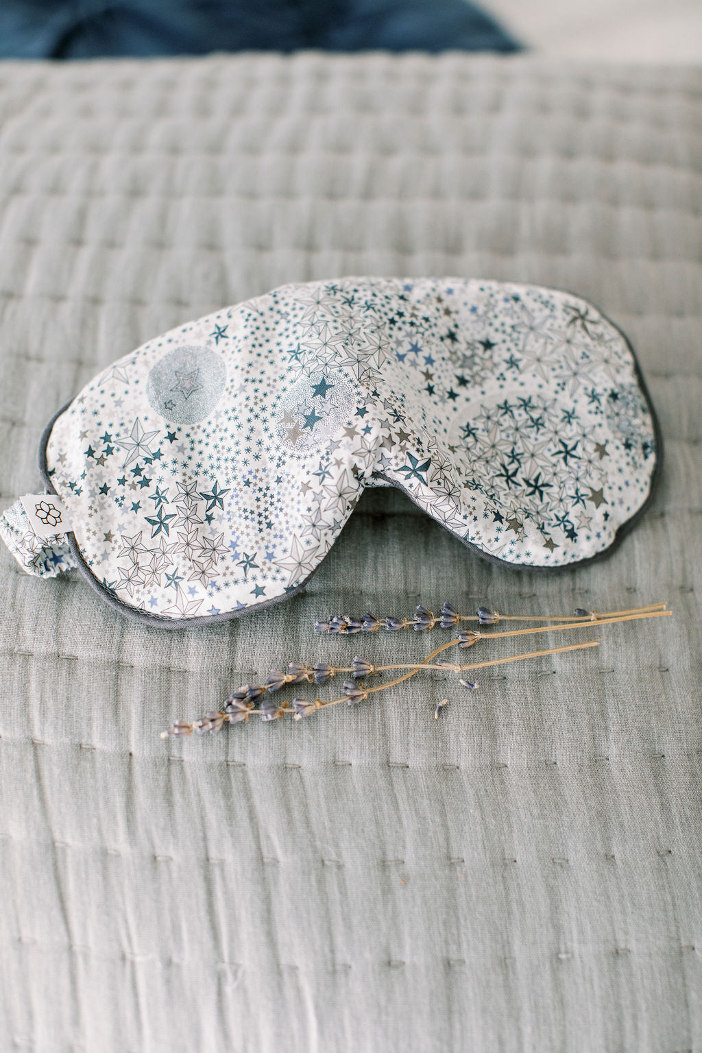 Sleep mask with star pattern on a textured surface with lavender buds