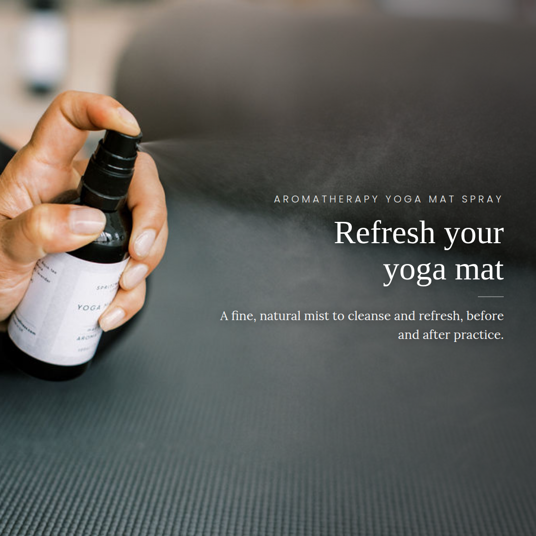 A hand sprays a fine mist from an aromatherapy yoga mat spray bottle onto a dark textured yoga mat, with white text on the right reading 'Refresh your yoga mat' and 'Aromatherapy Yoga Mat Spray'.