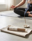 Palo Santo incense burning on a ceramic holder beside a yoga mat, Spritz Wellness